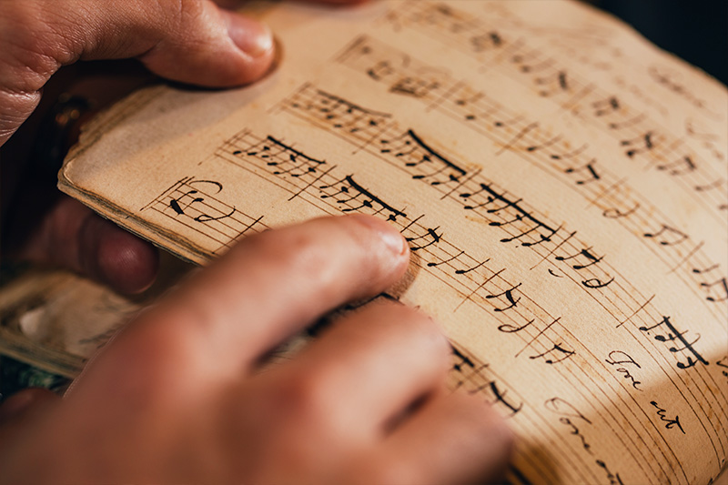 close up of a students hand following musical notes on the page of a book with their finger